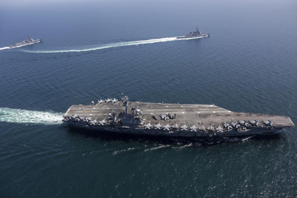 USS Abraham Lincoln carrier strike group sails with Japanese destroyers in the Sea of Japan under cloudy skies.