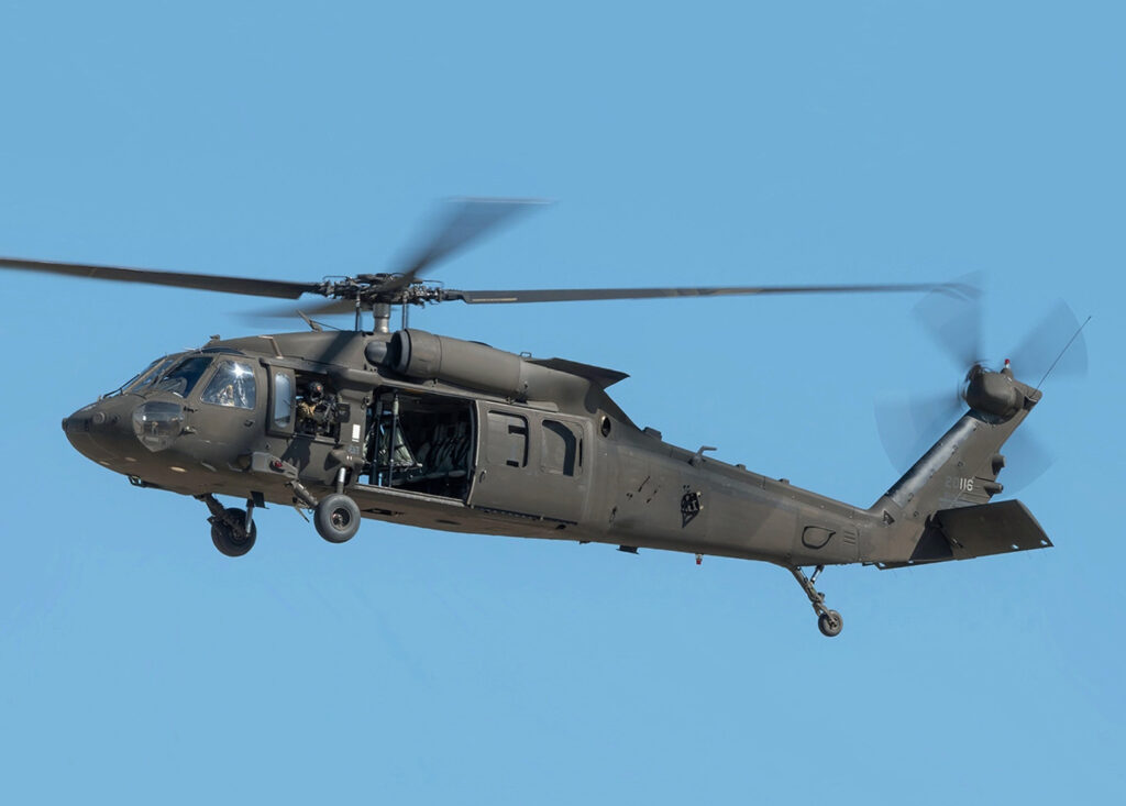 A Sikorsky UH-60 Black Hawk helicopter in flight over a forested area, similar to the one that crashed near Summit Lake.