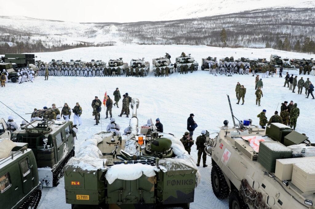 U.S. Marines and Norwegian soldiers stage amphibious vehicles on a snow-covered Arctic beach during NATO Cold Response drills near Bardufoss airbase.